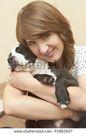 Young attractive female embracing her Pit Bull puppy