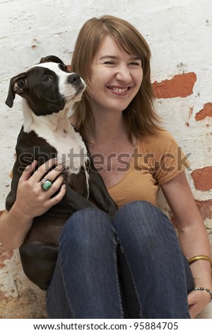 Pit Bull puppy sitting on lap of smiling dog owner