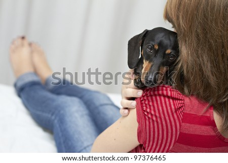 Lady wearing red shirt holding Dachshund dog breed