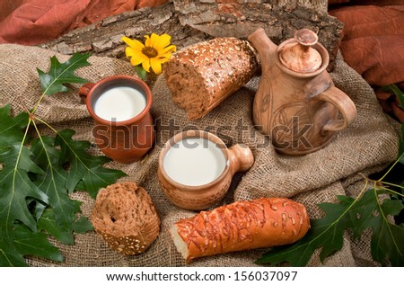 organic natural foods bread and milk in a clay pot on the tablecloth with flower