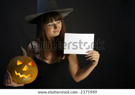 Witch with isolated white card and a pumpkin