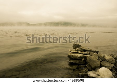 Beautiful water landscape with a fog above water & stones on a foreground. Vintage tone image