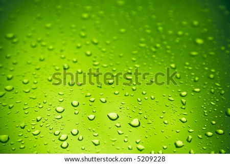 Warm toxic-green water drops over glass background