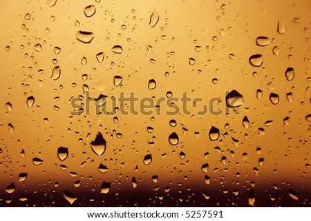 Warm colored orange heavy water drops over glass background with dark lower part