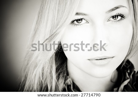 Head and shoulders portrait of young blond girl with beautiful eyes. Woman looking to camera, focus on eyes.