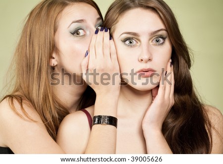 One girl whispering to other some news. Surprised face and palm near face in second girl