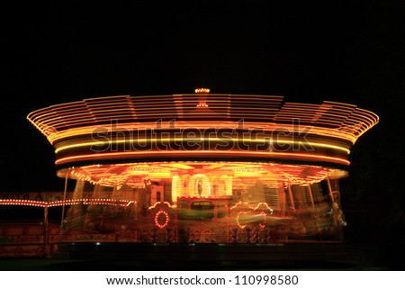 Merry go round at a fun fair at night captured using a slow shutter speed