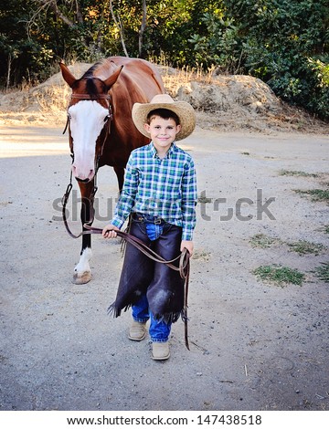 Young boy dressed as Cowboy leading Paint Horse