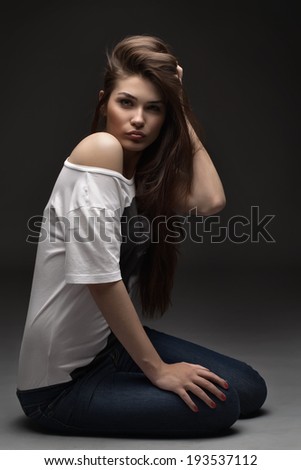 the beautiful girl poses in studio on a gray background. fashion portrait. make-up. long hair.