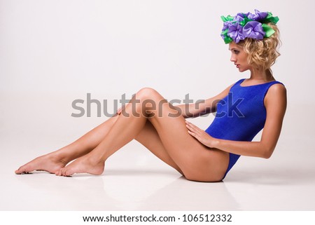 Sexy women in swimsuit with flowers in her hair. Sitting on floor isolated on white background