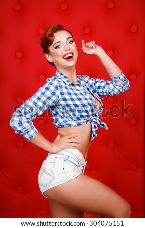 Sexy retro pin up girl in short shorts, isolated on red