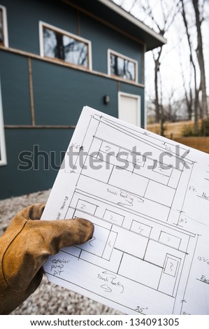 construction worker holding the blue prints for the building in the background
