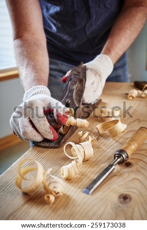 a man doing woodwork by using an old plane