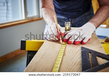 a man using a tape measure and pencil
