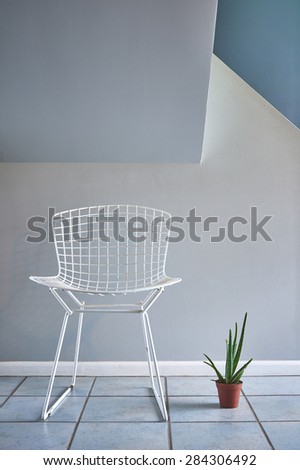 a modern mid century wire chair and a potted plant