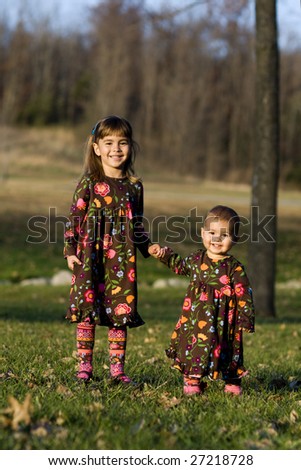 Two little girls holding hands at the park