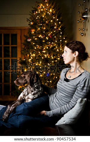Young woman and her dog watching television at Christmas time
