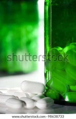 Pile of pills next to a pill bottle