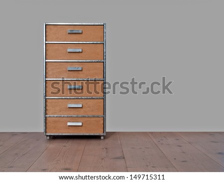 Chest of drawers of wood and metal, standing on a wooden plank floor