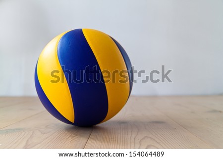 Blue and yellow volleyball on wooden floor