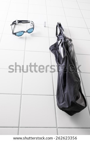 Blue swim goggles and a swimming suit hanging on hooks