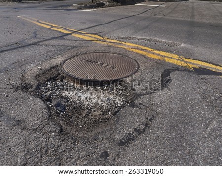 Large deep pothole an example of poor road maintenance due to reducing local infrastructure repair budgets