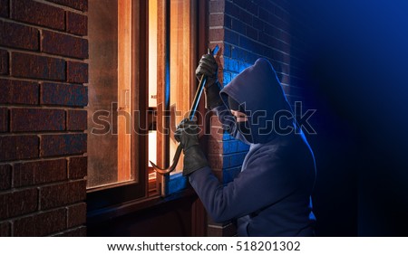 Burglar Using Crowbar To Break Into a House at night with room left and right for type