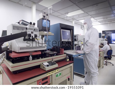 Technician operating various wafer testing equipment in clean lab