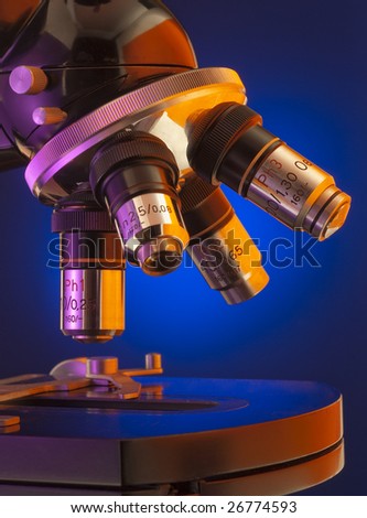 Close up of four lens microscope turret on blue background