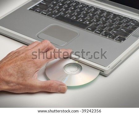 male hand loading cd or dvd into laptop computer