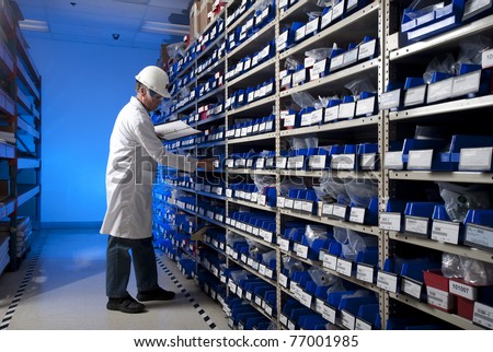 Worker checking inventory in stock room of a manufacturing company