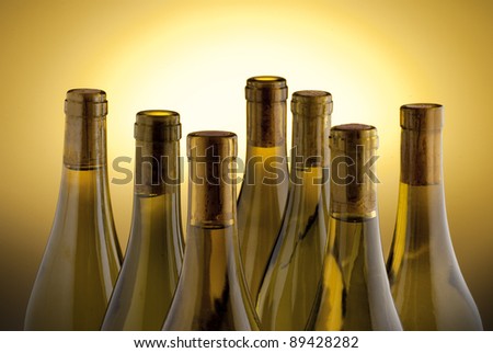 White wine bottles back lit by a yellow spot light