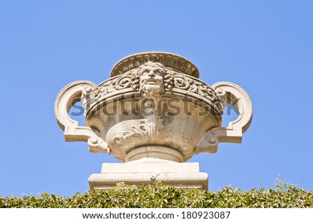 Picture of a marble vase with a human face Greek style. Decorative architecture in a public park.