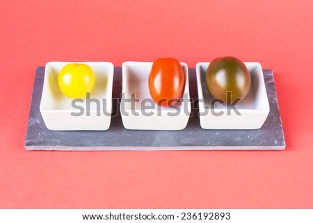 Yellow, red and brown cherry tomatoes on small plates
