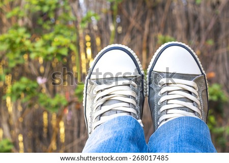 Feet wearing sneakers over garden background