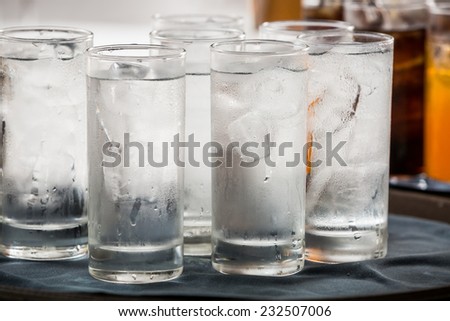 many glass of ice water are on a tray
