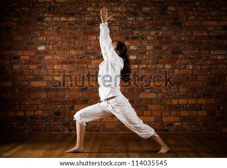 Girl exercising yoga against brick wall