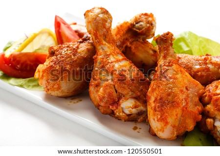 Grilled chicken drumsticks and vegetables on white background