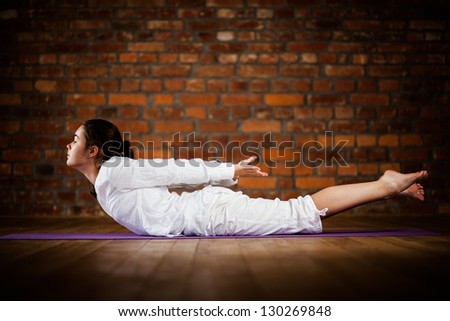 Girl exercising yoga against brick wall