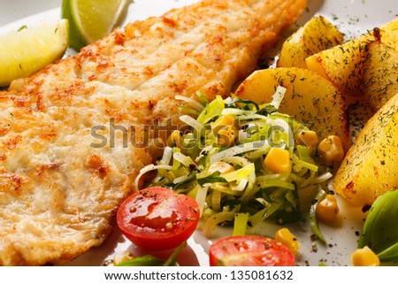 Fish dish - fried fish fillet with baked potatoes and vegetables