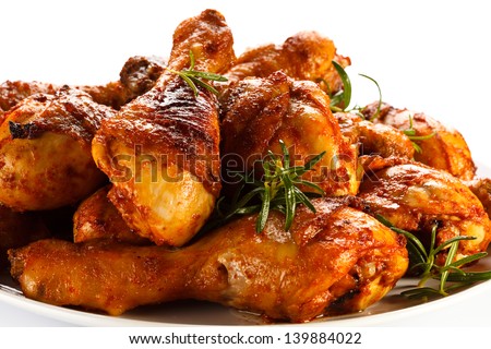 Grilled chicken drumsticks and vegetables on white background