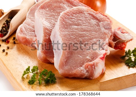 Fresh raw pork chops on white cutting board