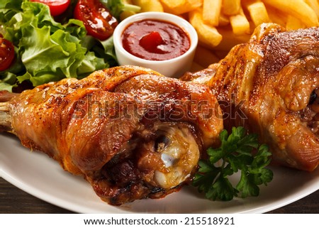 Grilled turkey legs with French fries and vegetables