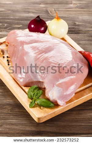 Raw turkey fillet on cutting board on white background