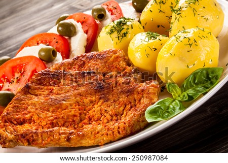 Fried pork chops, boiled potatoes and caprese salad