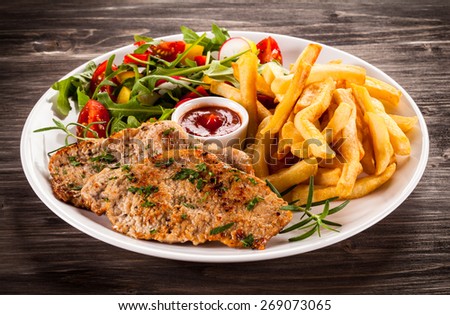 Fried steaks, French fries and vegetables