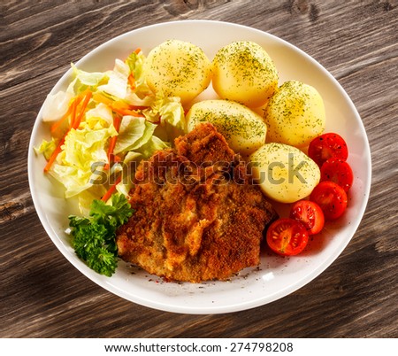 Fried pork chop, boiled potatoes and vegetable salad