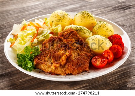 Fried pork chop, boiled potatoes and vegetable salad