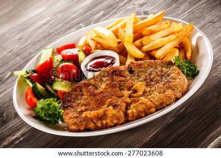 Fried pork chop, French fries and vegetable salad