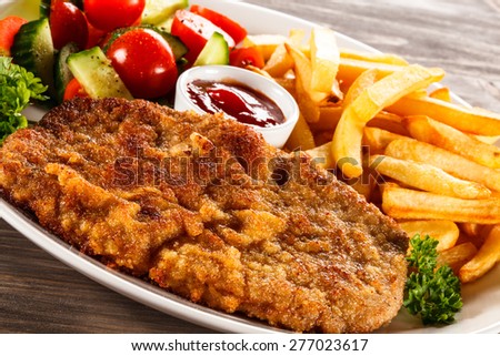 Fried pork chop, French fries and vegetable salad